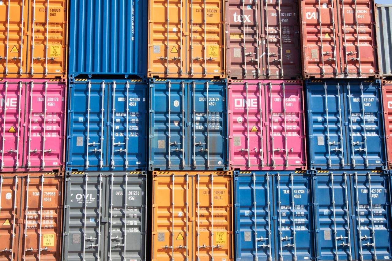 our-services-1 Stacked multicolored shipping containers at a Hamburg port, showcasing industrial logistics.