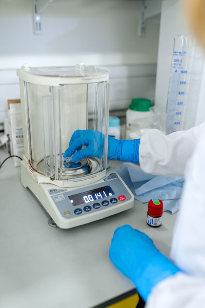 ours-journey Scientist uses digital scale for precise measurements in a lab setting.