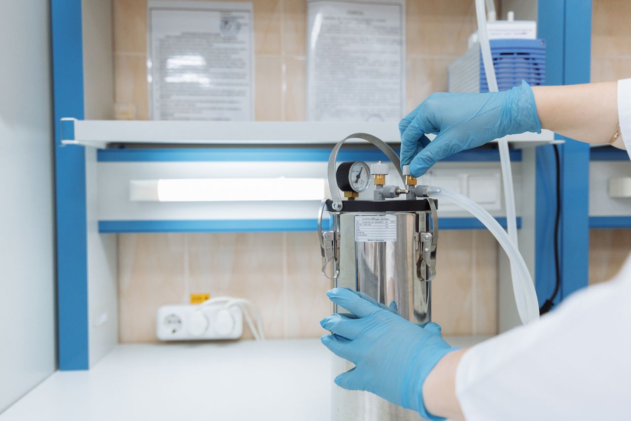 our-experience Scientist adjusting laboratory equipment with precision in a modern lab setting, wearing blue gloves.